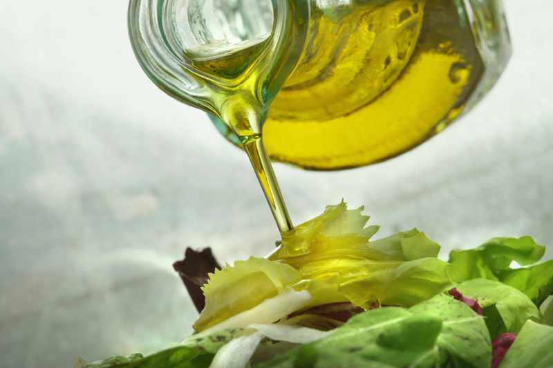 Olive oil is poured out of an carafe on a salad.